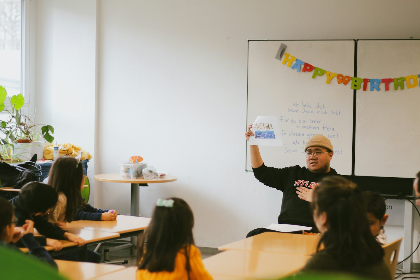 Teacher shows a drawing to children in a classroom.