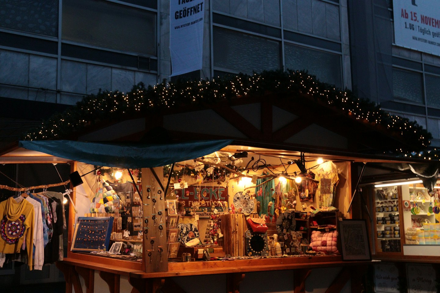 A decorated market stall displays handmade crafts and jewelry at night.