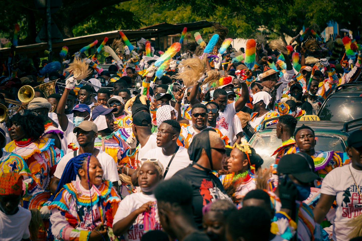 A large crowd in traditional clothing celebrating with brass instruments.